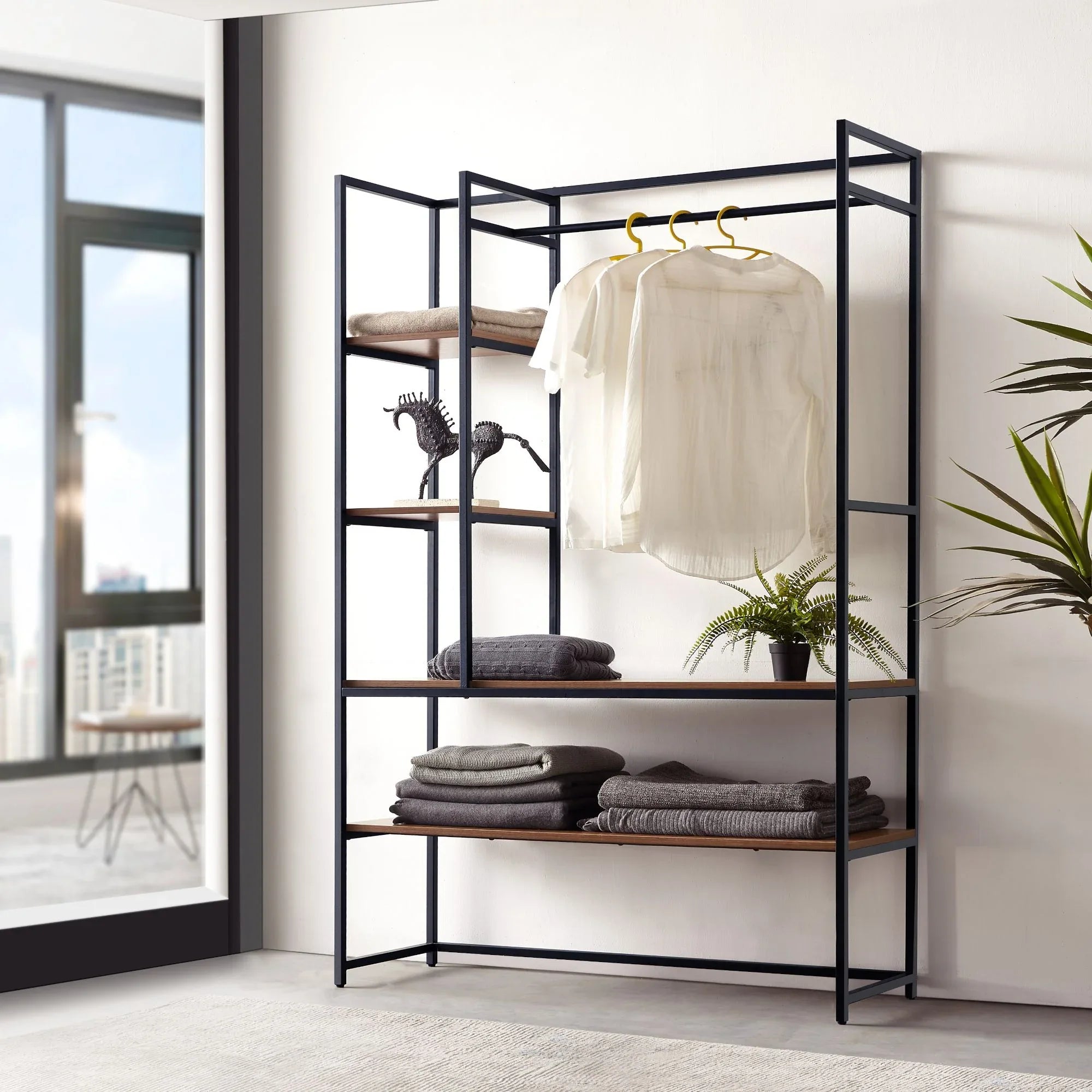 Black metal clothes stand with shelves and side rails for hanging clothes.