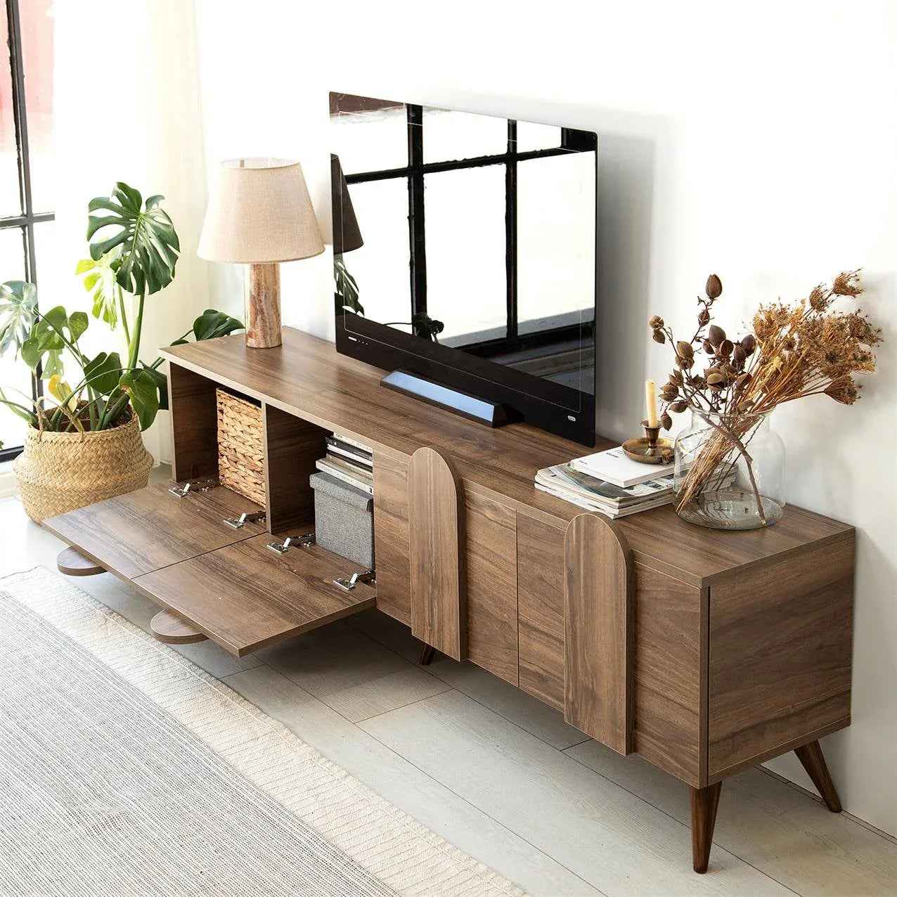 Light wood TV console with center pull-out panel and storage cabinets, angled view