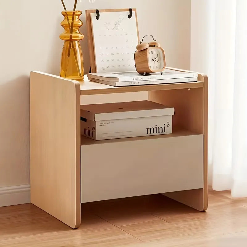 Wooden nightstand with books, alarm clock, and decorative items on a wooden floor.