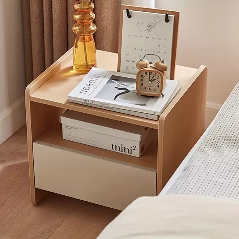 Wooden nightstand with books, a clock, and a calendar in a bedroom setting.