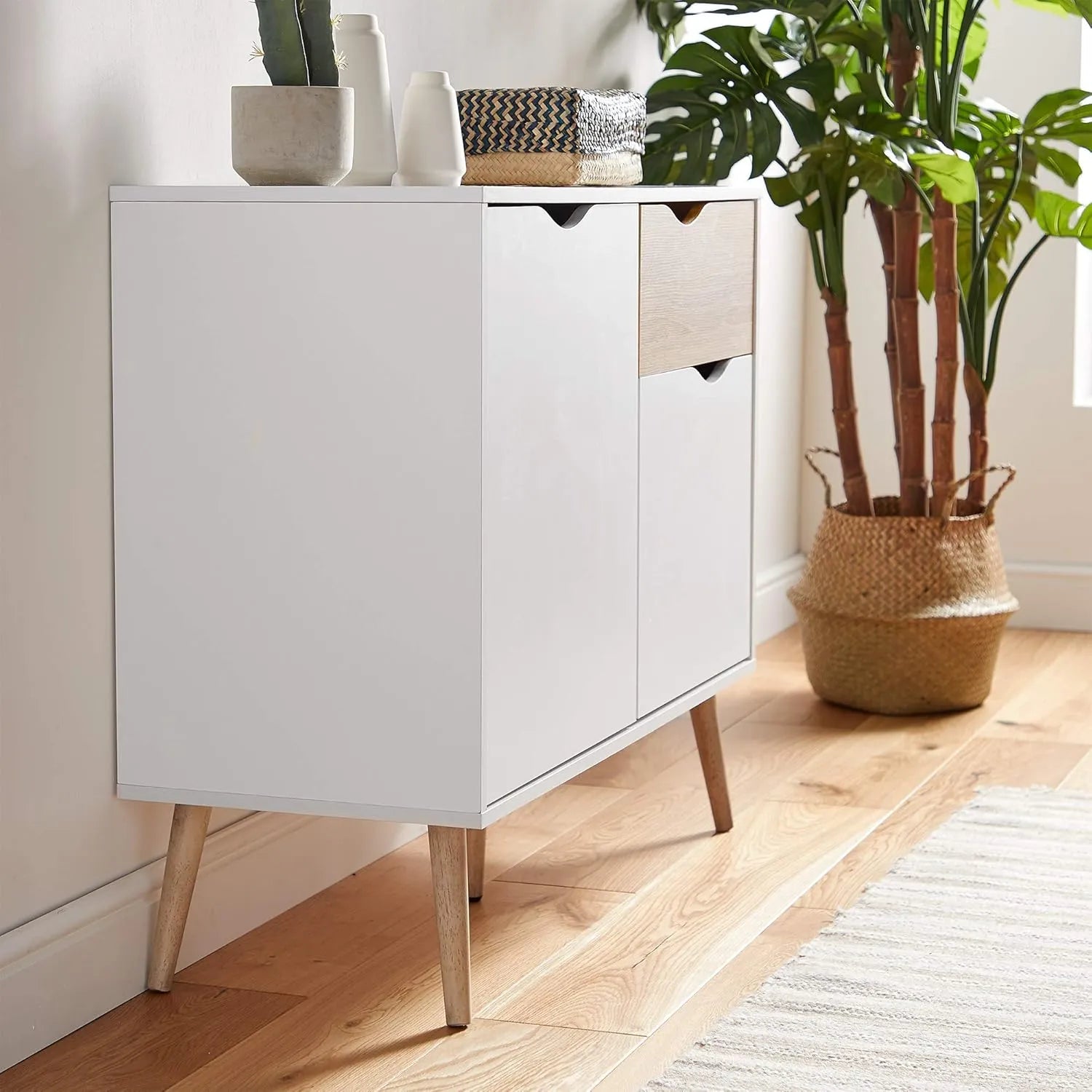 White coffee cabinet with oak-tone drawer fronts, two doors, and angled wooden legs
