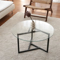 Round glass coffee table with dark metal cross base